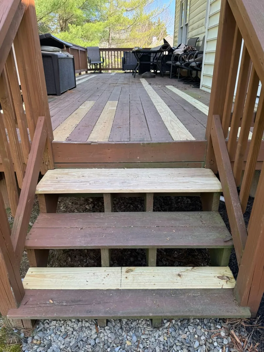 Wooden deck stairs mid-repair, showing new pressure-treated boards swapped in next to the original weathered treads