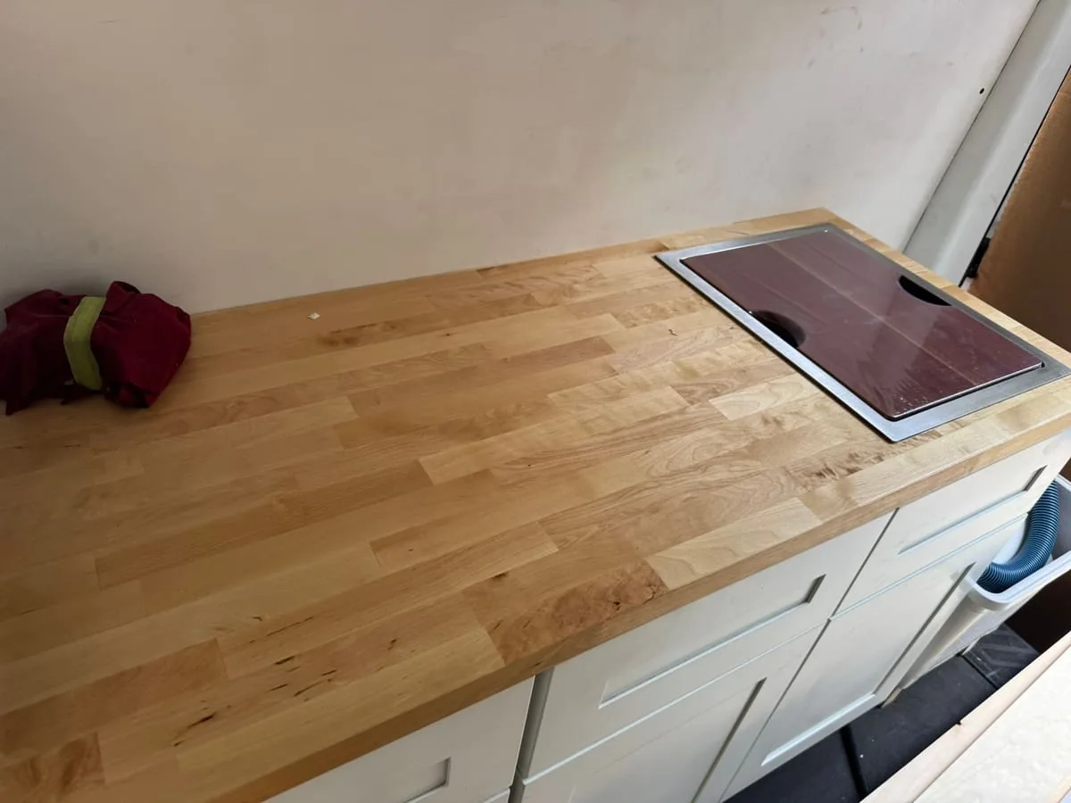 New butcher block countertop with a flush-mounted induction cooktop, fitted over white shaker-style cabinets