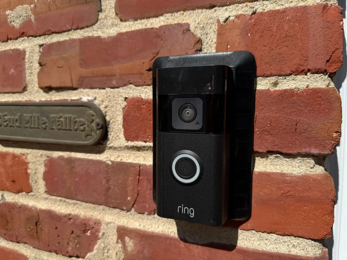 Ring video doorbell mounted on a brick entryway corner next to a white door frame