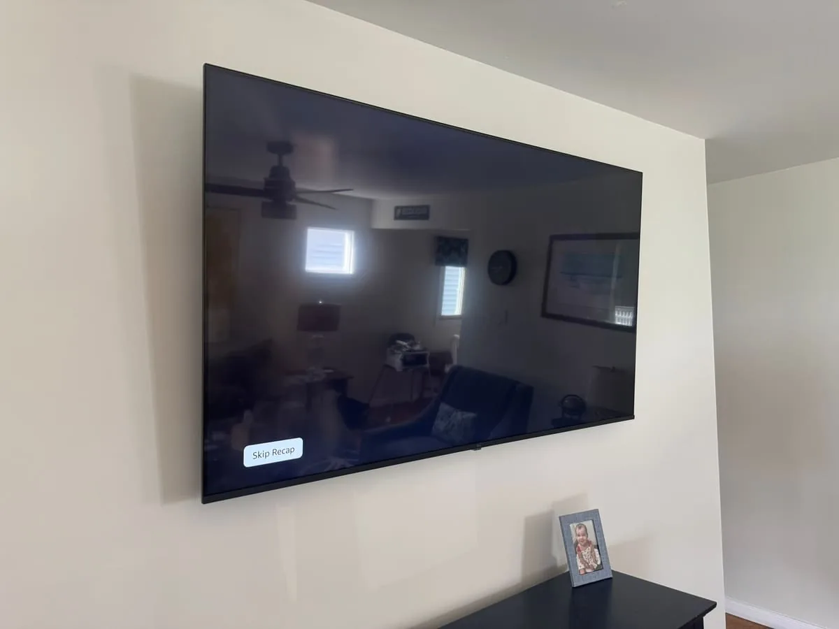 Large flat-screen TV flush-mounted above a media console, with cables concealed behind the wall