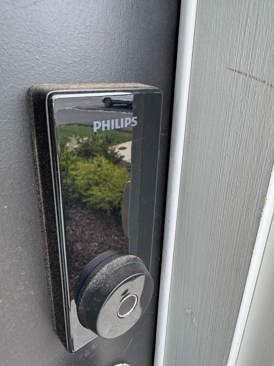 A Philips smart deadbolt on the exterior face of a charcoal front door, photographed after the strike was adjusted so the bolt throws cleanly.