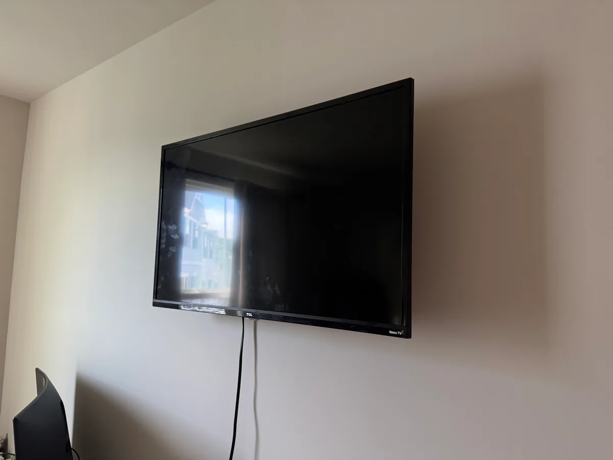 A small TV wall-mounted in a guest bedroom, framed tight against a pale wall.